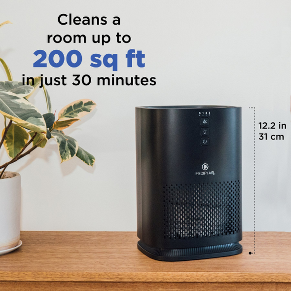 A black air purifier sits on a table. Text reads "Cleans a room up to 200 square feet in just 30 minutes."