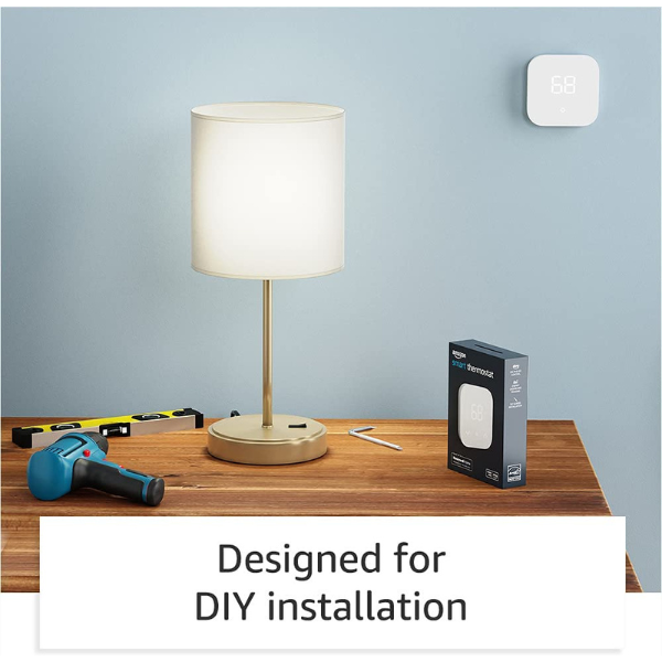 A desk with a drill, level, and hex key sitting next to an Amazon smart thermostat box. The thermostat is on the wall and a text box reads "designed for DIY installation"