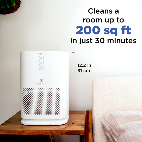 The air purifier on a side table. Measures 12.2 inches (31 cm) tall. Text reads Cleans a room up to 200 square feet in just 30 minutes.