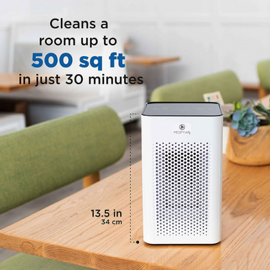 The air purifier on a table. Measures 13.5 inches (34 cm) tall. Text reads Cleans a room up to 500 square feet in just 30 minutes.