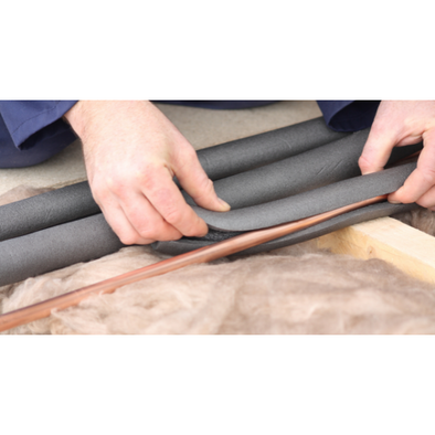 A person installs pipe wrap around a copper water pipe.